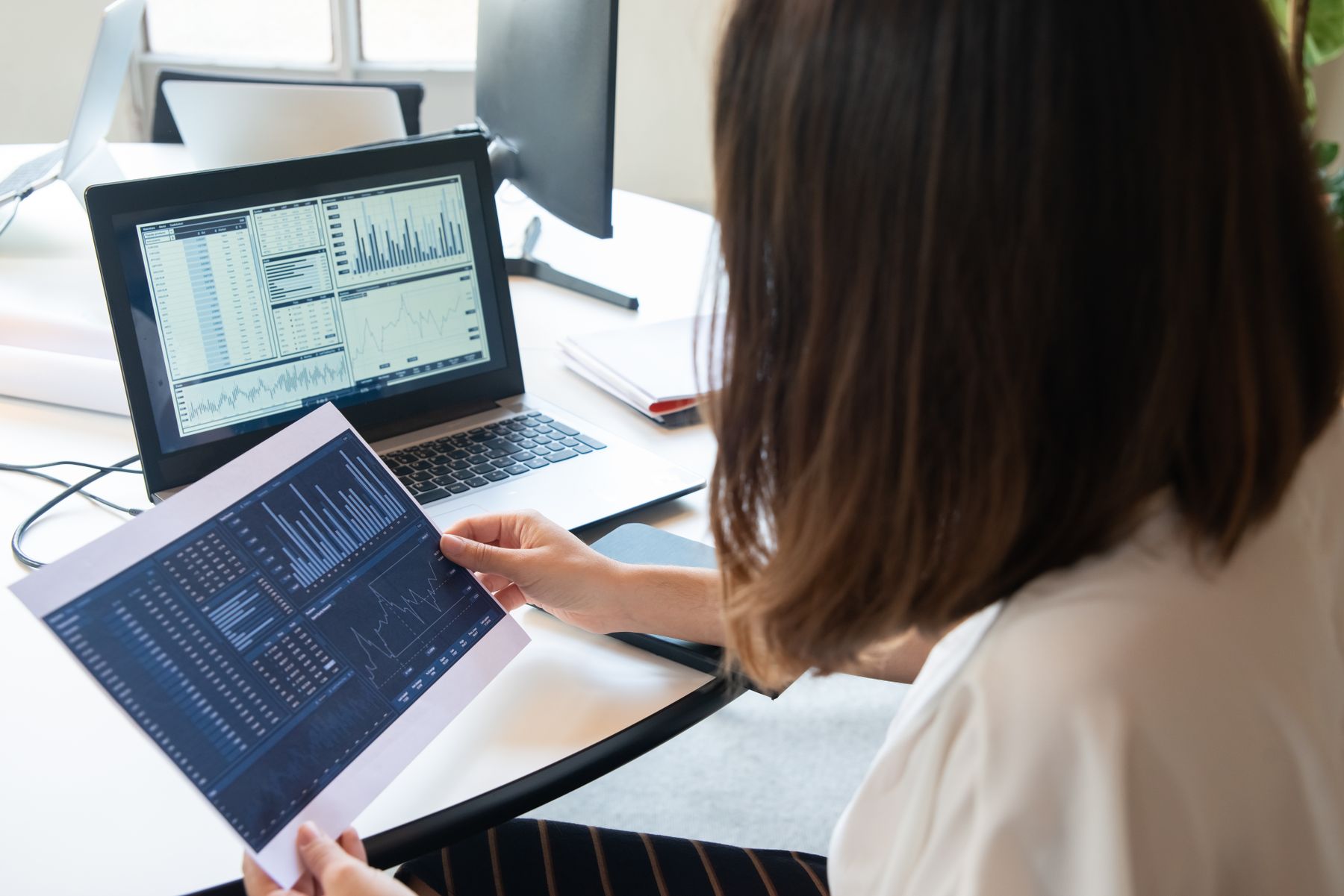 Developer evaluating financial market data dashboards on a laptop and printed report